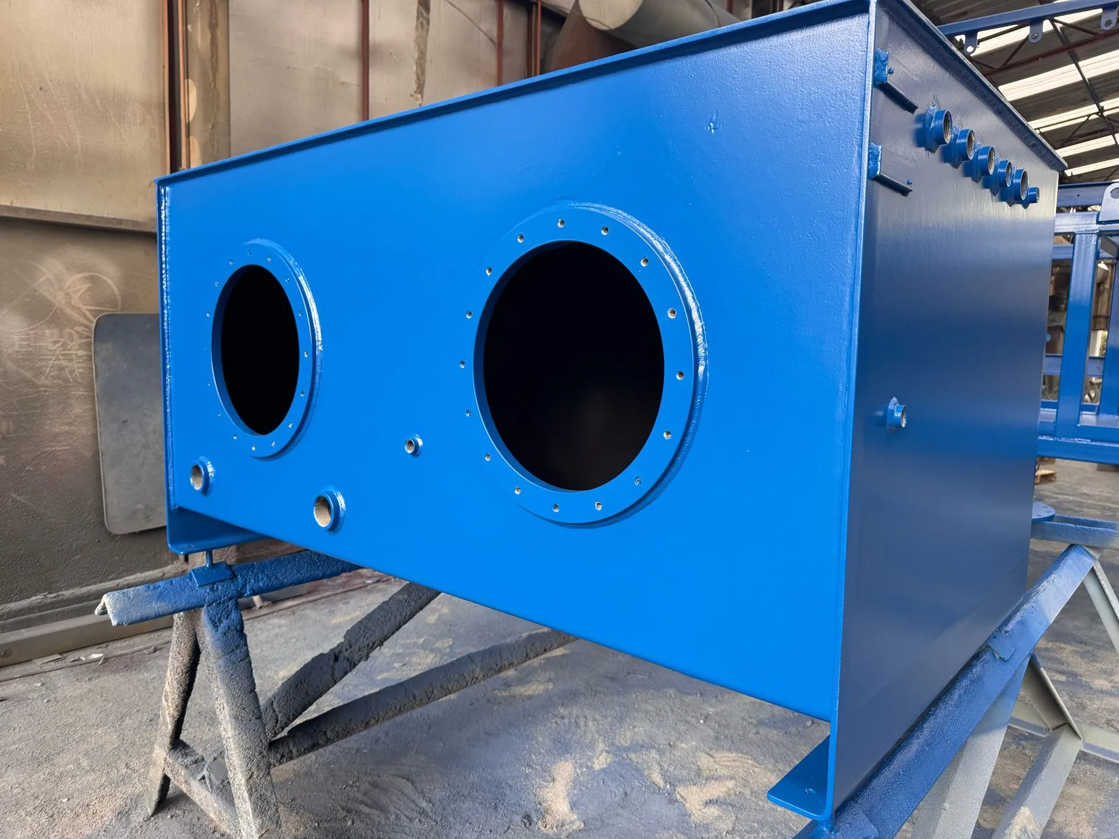 Superficie azul revestida de equipo industrial, con conexiones circulares