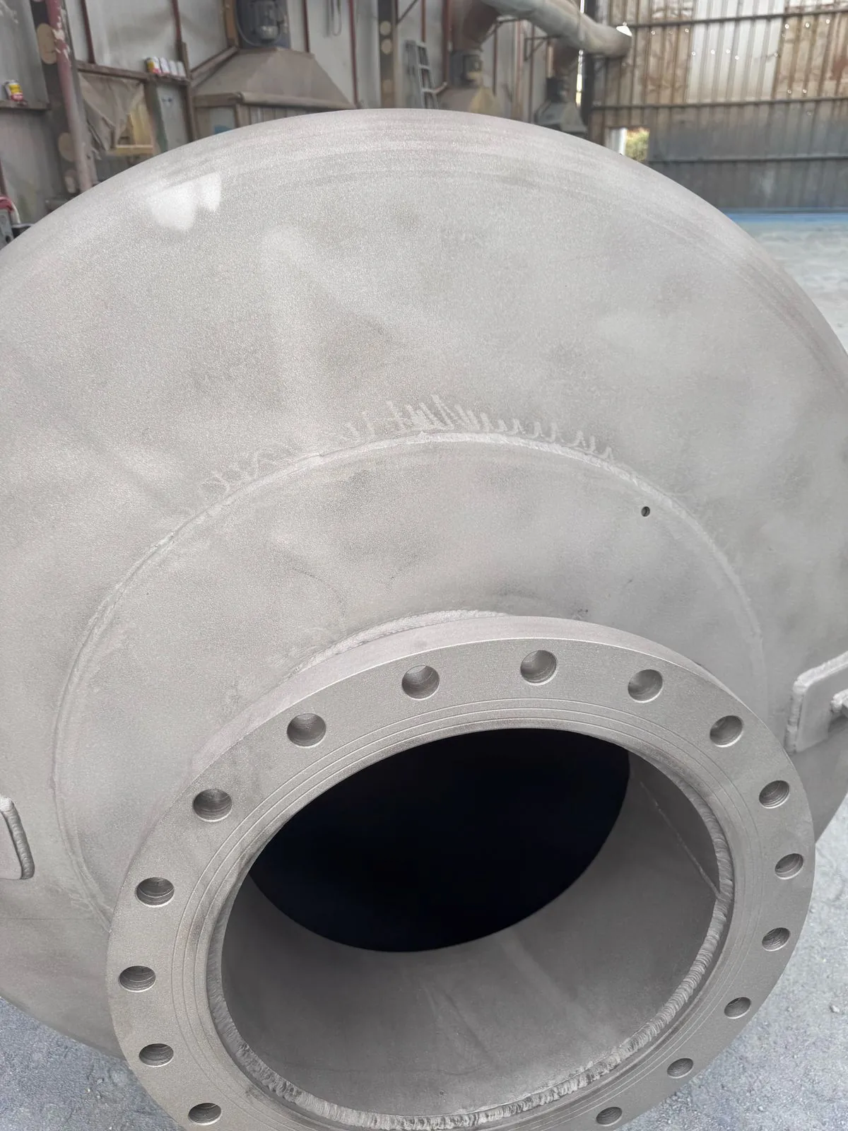 Detalle real de una pieza metálica con superficie gris preparada, con brida circular